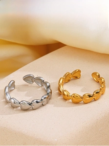 Detail of adjustable heart rings in gold and silver finish on a textured stand