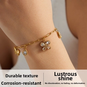 Close-up of gold-plated paperclip chain bracelet with butterfly and zircon charms