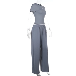 Détail de la broderie sport life blanche sur le t-shirt ajusté gris foncé et le pantalon large