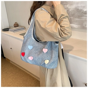 Vue détaillée du sac à bandoulière bleu jean avec patchs en forme de cœur et bordure argentée