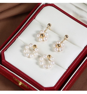 Macro detail of freshwater pearl flower and hoop earrings inside a red jewelry box