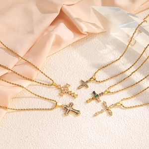 Gold stainless steel cross necklace set with colorful crystals on elegant silk background