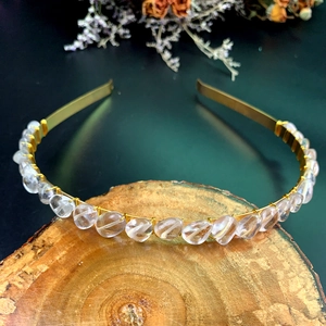 Detailed view of handmade crystal crown headband with gold wire on a rustic wooden base