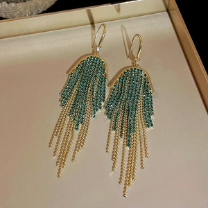 Detailed shot of U-shaped fringe earrings with green rhinestones and gold chains