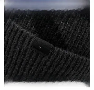 Close-up of black ribbed knit beanie featuring a square logo patch and warm winter texture