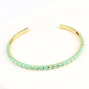 Close-up of golden open bangle with mint green spiral enamel finish in bohemian style
