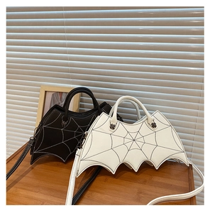 Black and white bat-shaped punk handbags with spider web embroidery on a wooden table