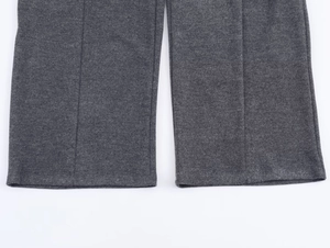 Detail view of dark grey twill trousers showing textured fabric and vertical seam stitching