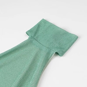 Close-up of sparkling green party dress fabric with feather detail and textured finish