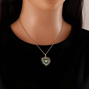 Détail du collier cœur doré avec émail vert et design de rayons de soleil
