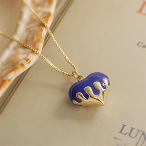 Collana cuore lava con ciondolo a goccia blu e finitura oro su sfondo di libro