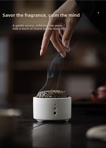 Close-up of ceramic incense burner with brass lid and rising smoke on wood surface