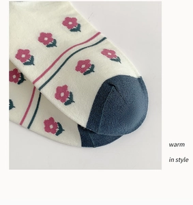 Détail d'une chaussette en coton tricoté avec motif floral et pointe bleu marine contrastée