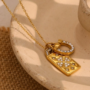 Close-up of 18K gold plated horseshoe and heart pendant necklace on ceramic plate