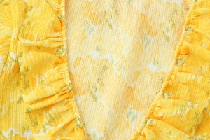 Close-up of yellow floral seersucker fabric with ruffle details and textured pattern
