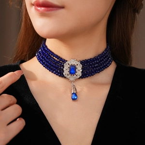 Macro shot of vintage style multi-strand blue beaded choker with pear-shaped gemstone pendant