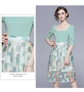 Detail of green knit top and beige mesh skirt with colorful geometric embroidery