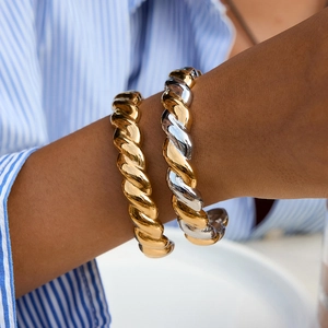 Adjustable twisted cable cuff bracelets in gold and two-tone finishes on a wrist