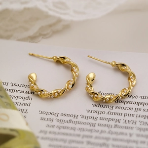 18K gold plated copper earrings with twisted design and small pearls on lace background