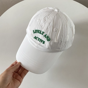 Close-up of white nylon quick-dry baseball cap with green embroidered text.