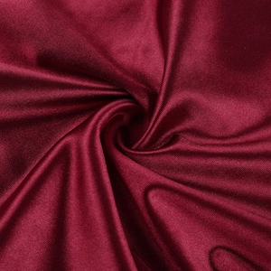 Détail macro du tissu satiné bordeaux avec texture plissée élégante et éclat soyeux