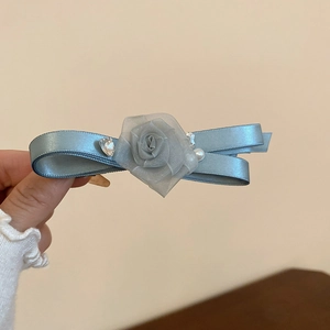 Close-up of blue satin bow hair clip with fabric rose, rhinestones and white pearl