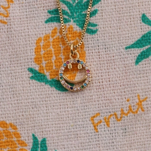 Gold smile necklace with colorful zircon stones on fruit pattern fabric background