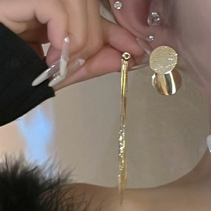 Golden tassel earrings with round textured metal disc worn by a model in lifestyle view