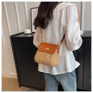 Detail of straw woven crossbody bag with brown leather flap and golden twist lock