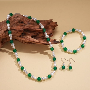Three-piece jewelry set with green agate style beads and pearls on natural wood