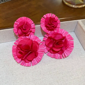 Close-up of pink raffia floral tassel earrings on a display tray for a resort look