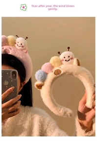 Close-up of pink plush headband featuring cute cartoon insect dolls and colorful pom poms