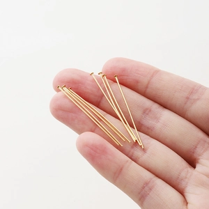 Close-up of 18K gold plated T-pins for DIY jewelry making held by hand on white background