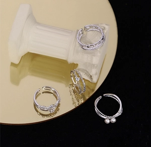 Luxe display of silver adjustable rings with pearls and zircons on gold mirror
