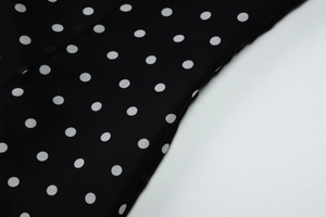 Close-up detail of high-quality black and white polka dot fabric texture and draped folds