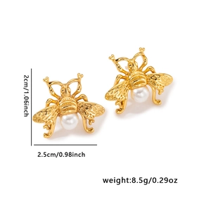 Detail shot of vintage gold-plated bee earrings with white pearl and textured wings