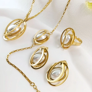 Detailed view of golden jewelry set featuring oval white faux pearls on earrings and rings