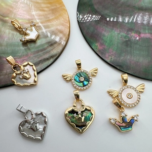 Macro detail of 18K gold plated heart and crown pendants with natural abalone shell