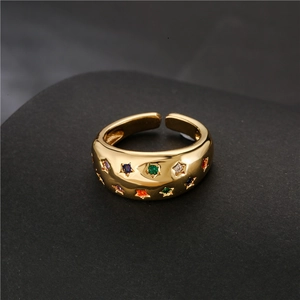 Gold plated open ring with colorful star-shaped zircons on a gray pedestal
