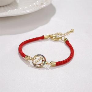 Detail of red braided MAMA bracelet featuring gold charm with colorful zircon stones