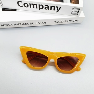Close-up of vibrant orange cat eye sunglasses with brown lenses on a modern prop book