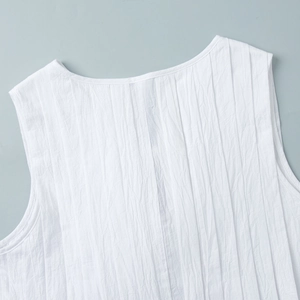 Détail de robe sans manches blanche avec plis verticaux et encolure ronde affinée