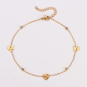 Detailed view of gold anklet with heart LOVE charms and shimmering crystals on white