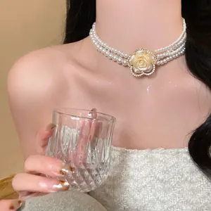 Detail of multi-layer pearl choker featuring a crystal rose pendant on the neck