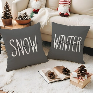 Detail of dark grey linen Christmas pillow covers with winter typography on a sofa