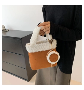 Detail of faux shearling trim and suede texture on a brown bucket bag with a mini pouch