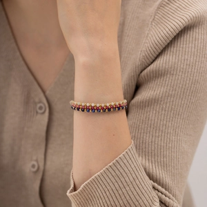 Close-up of white, red, and blue beaded layered bracelets with gold accents on wrist
