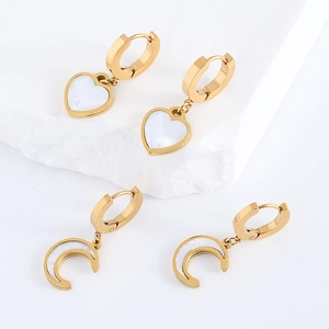 Gold stainless steel hoop earrings with heart and moon mother-of-pearl charms on marble