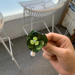 Close-up of green resin flower earring with shimmering center stone and pearl drop charm