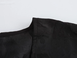 Detailaufnahme des schwarzen Jacquard-Stoffes am eleganten V-Ausschnitt Kleid